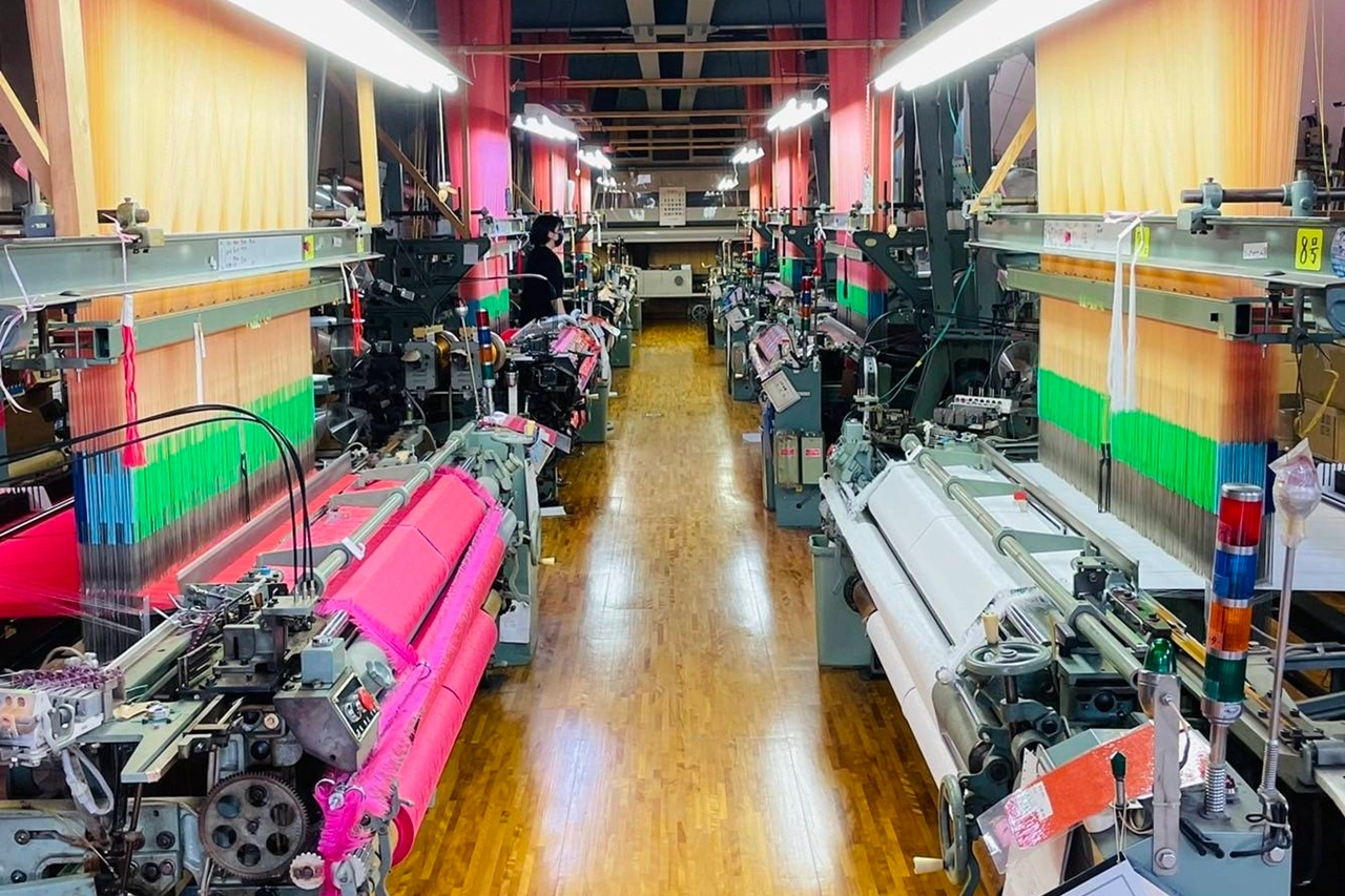 光織物のジャカード織機が並ぶ工場